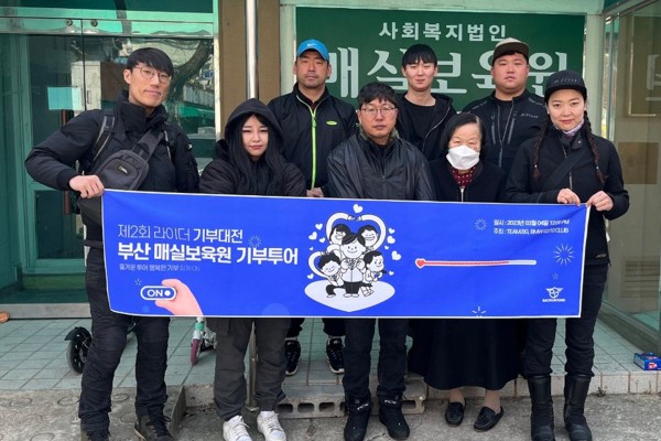 매실보육원 입구에서 현수막을 들고 선 기부 활동 참여자들